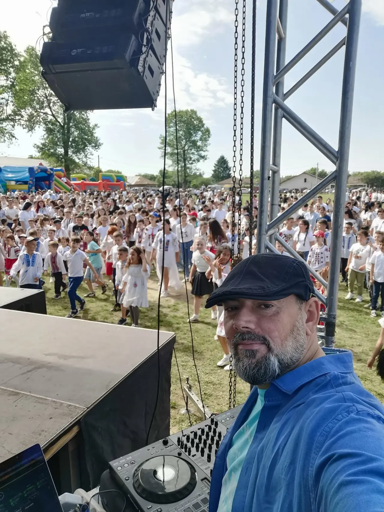 DJ Florin Popescu la un eveniment în aer liber, cu sute de oameni în costume populare în fața scenei