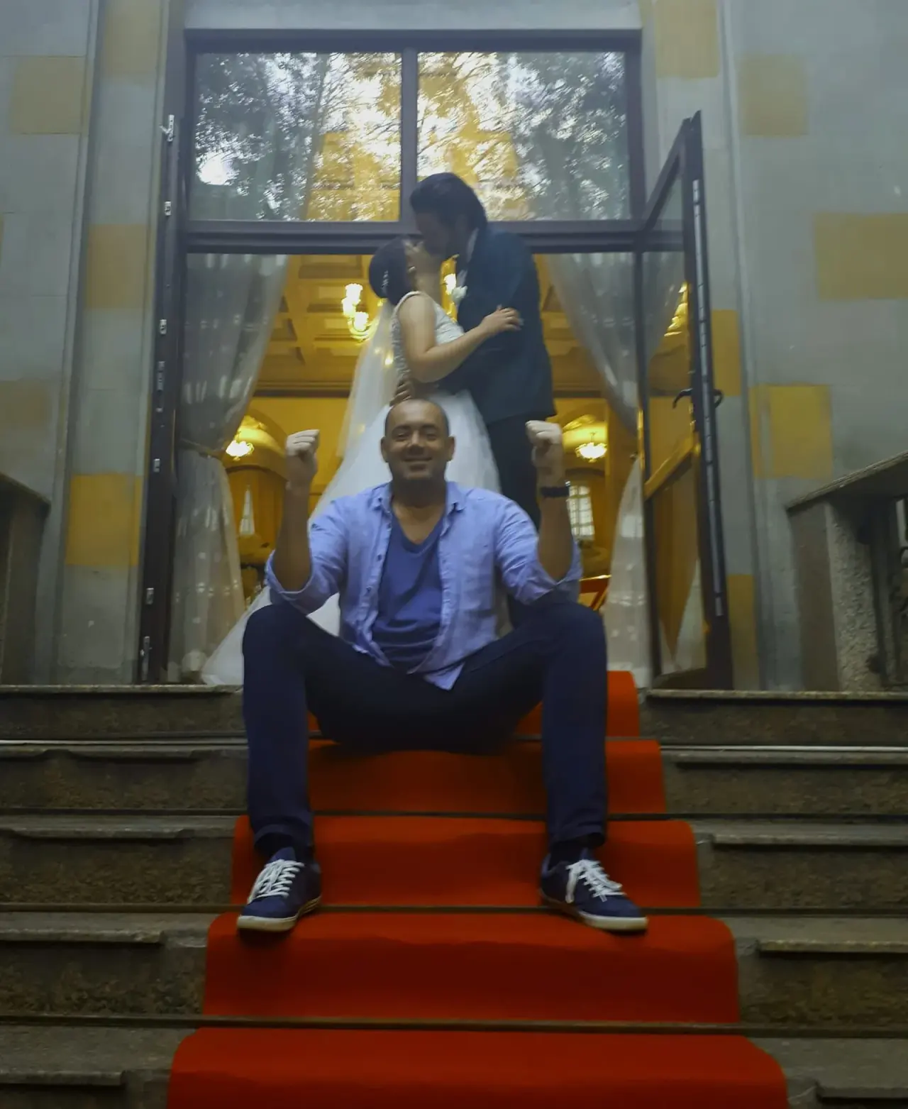 DJ Florin Popescu pe scările cu covor roșu, cu mirii sărutându-se în spatele lui