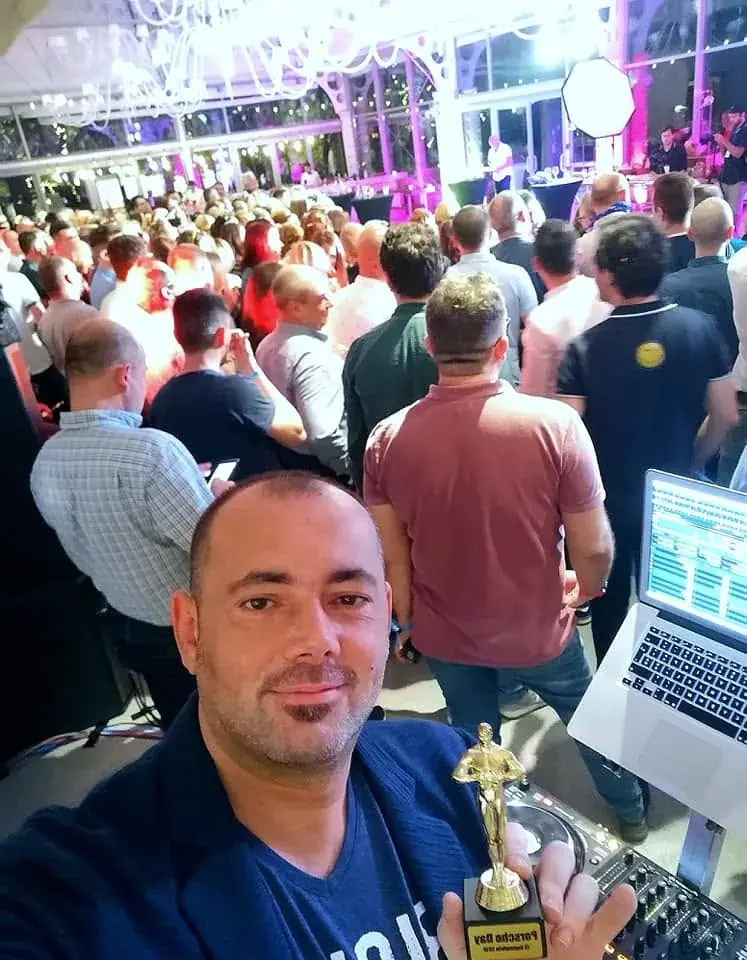 DJ Florin Popescu cu trofeul primit la un eveniment corporate, în fața invitaților